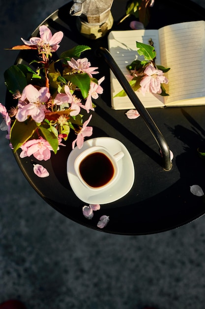 Fiori e taccuino della tazza di caffè sulla piccola tavola nera