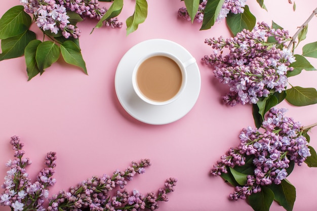 Fiori lilla viola e una tazza di caffè sul rosa pastello.