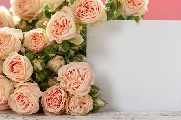 Fiori rosa delle rose con la carta di regalo sul rosa