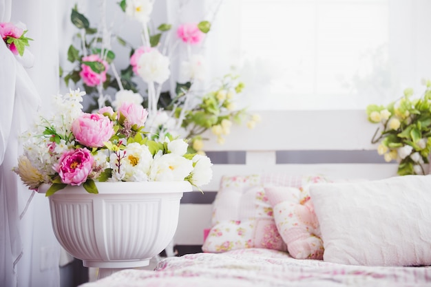 Fiori rosa e bianchi in un vaso vicino al letto