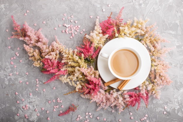 Fiori rosa e rossi di astilbe e una tazza di caffè