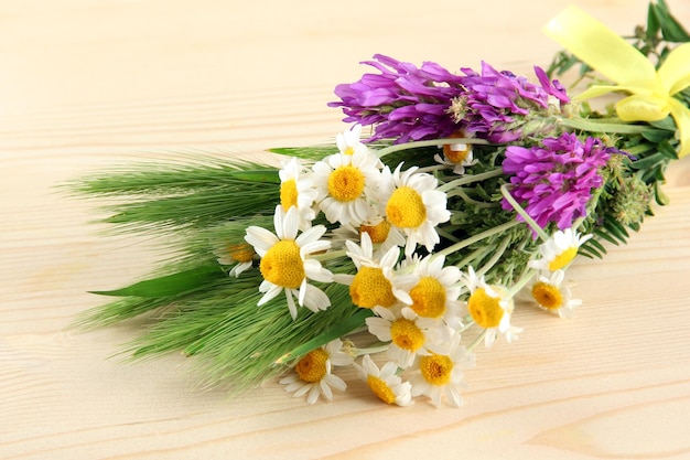 Fiori selvatici e spighette verdi su fondo di legno