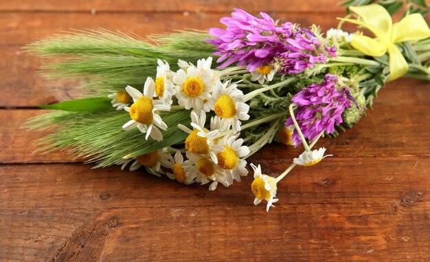 Fiori selvatici e spighette verdi su fondo di legno