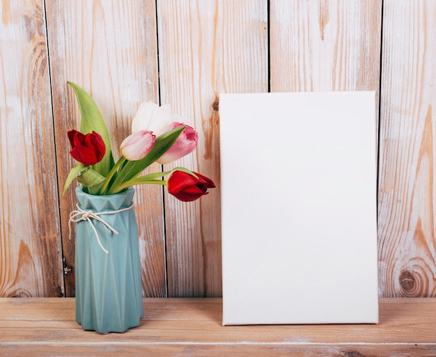 Fiori variopinti del tulipano in vaso con il contesto di legno del cartello vuoto