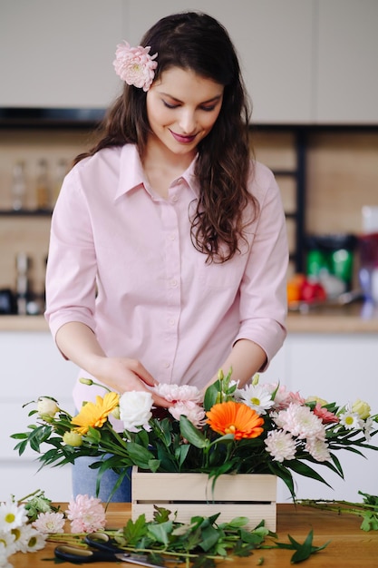 Fiorista al lavoro bella giovane donna bruna che fa moda composizione moderna di fiori diversi a casa