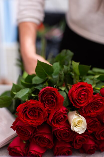 Fiorista al lavoro Primo piano mani femminili rose tagliate Donna che fa un mazzo di rose rosse per san valentino Rose fresche per la consegna del bouquet