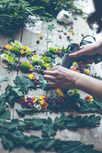 Fiorista che fa decorazioni floreali con lettere e colla. Colpo di luce naturale all'interno con una piccola profondità di campo