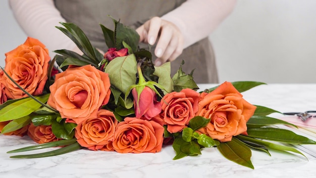 Fiorista che pota rose rosse per la disposizione dei bouquet.