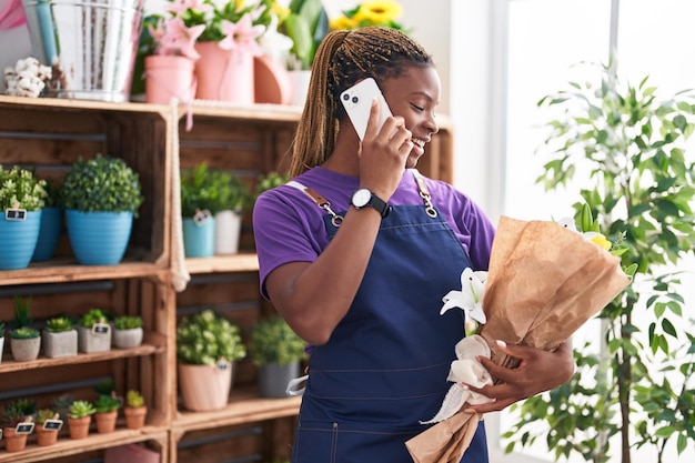 Fiorista della donna afroamericana che parla sullo smartphone che tiene i fiori al fiorista