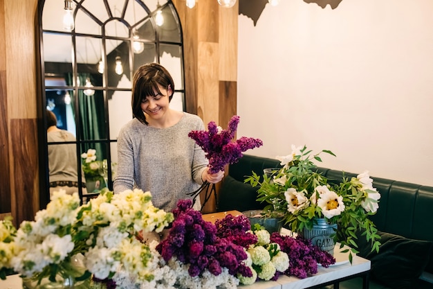 Fiorista della donna che fa il mazzo lilla nel negozio di fiori