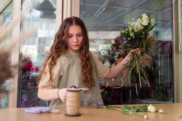 Fiorista di giovane donna lavora con fiori sul posto di lavoro concetto di piccola impresa stile di vita ritagliata ritratto fiori da vicino