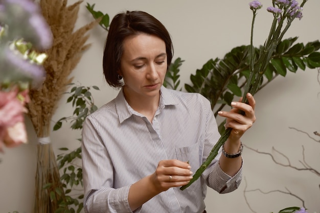 Fiorista di giovane donna nel suo studio facendo un bel bouquet