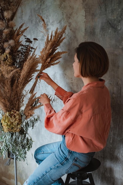 Fiorista donna decora un bouquet eterno di fiori secchi sul bancone del suo studio floreale