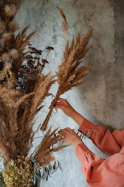 Fiorista donna decora un bouquet eterno di fiori secchi sul bancone del suo studio floreale