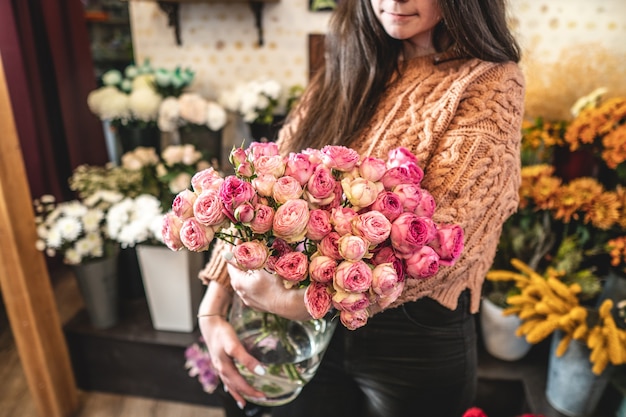 Fiorista donna detiene un bel mazzo di rose rosa in fiore in un negozio di fiori