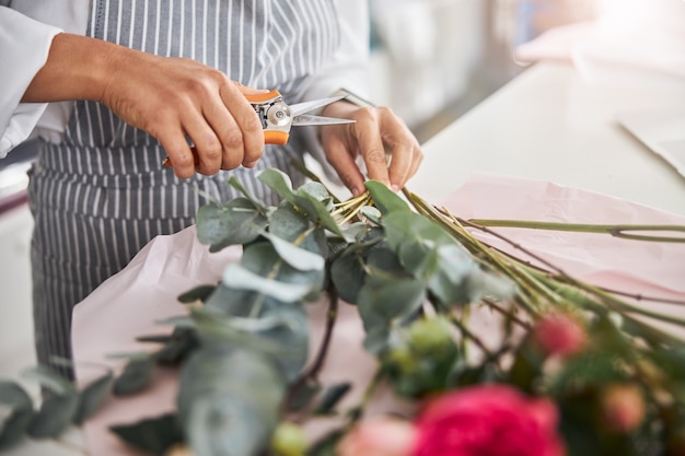 Fiorista esperto che taglia i fiori prima di fare un bouquet