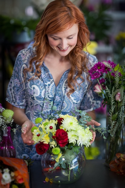 Fiorista femminile che controlla una disposizione di fiori in vaso