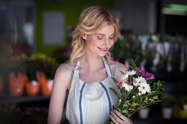 Fiorista femminile che tiene mazzo di fiore nel negozio di fiori