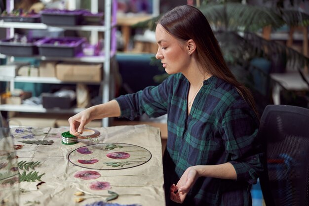 Fiorista femminile sicuro sta lavorando con fiori essiccati in un accogliente negozio di fiori