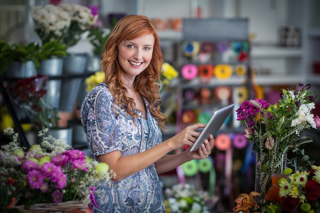 Fiorista femminile sorridente che per mezzo della compressa digitale