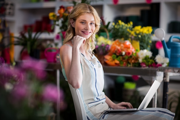 Fiorista femminile sorridente che utilizza computer portatile nel negozio di fiorista