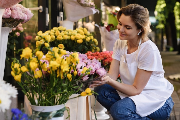 Fiorista giovane e bella donna che lavora nel suo piccolo negozio di fiori