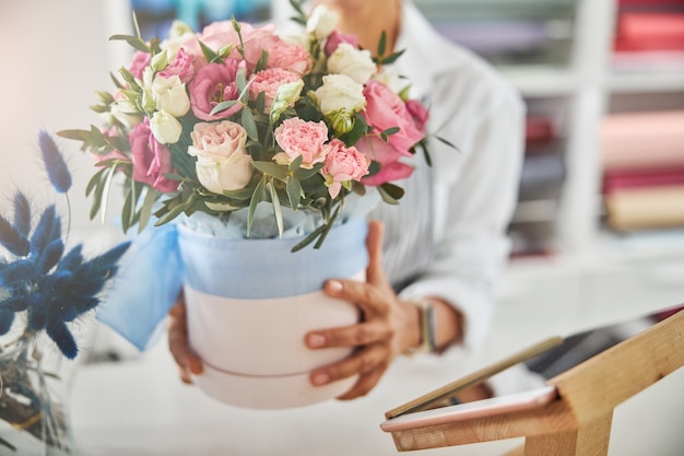 Fiorista professionista che mostra un vaso di fiori con rose