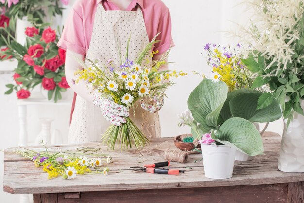 Fiorista ragazza fa bouquet di fiori di campo