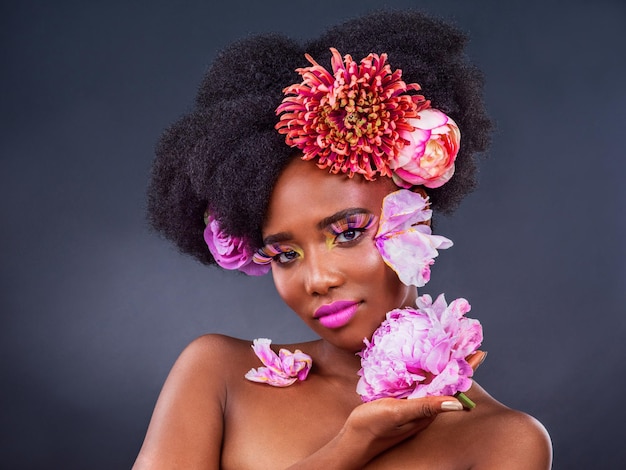 Fioritura in rosa Studio di una bella giovane donna in posa con fiori tra i capelli