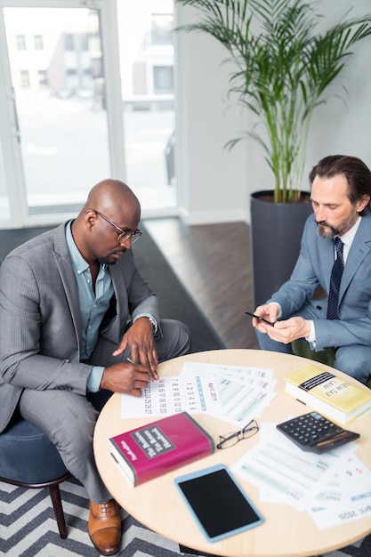 Firma del contratto. Vista dall'alto dell'uomo d'affari dalla pelle scura che firma un accordo con il partner commerciale