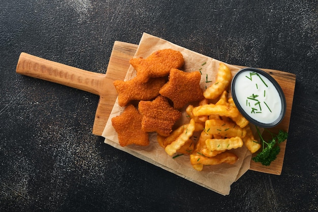 Fish and Chips fast food britannico Bastoncini di pesce con patatine fritte adagiati su tavola rustica su sfondo di cemento vecchio scuro Tradizionale cibo di strada autentico britannico o cibo da asporto Mock up Vista dall'alto