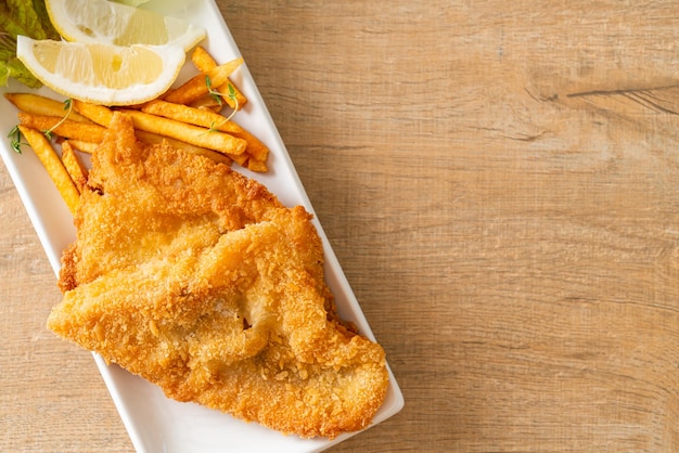 Fish and chips - filetto di pesce fritto con patatine fritte e limone su piatto bianco