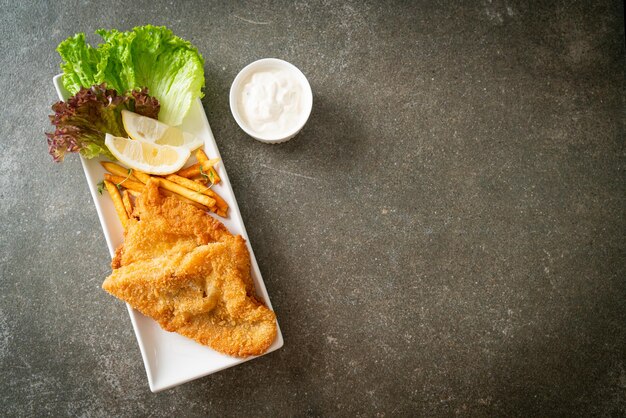 fish and chips - filetto di pesce fritto con patatine fritte e limone su piatto bianco