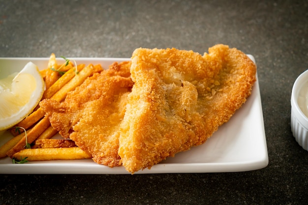 fish and chips - filetto di pesce fritto con patatine fritte e limone su piatto bianco