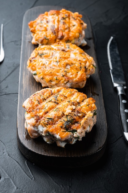 Fishcakes alla griglia impostato, su sfondo nero con texture