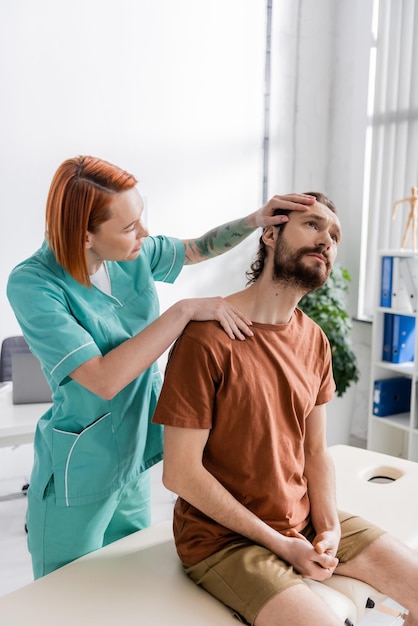 fisioterapeuta che allunga il collo del paziente durante la diagnosi nel centro di riabilitazione