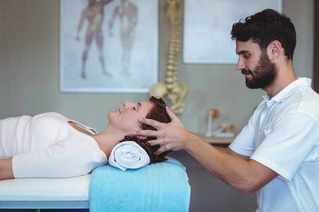 Fisioterapista che dà massaggio alla testa di una donna