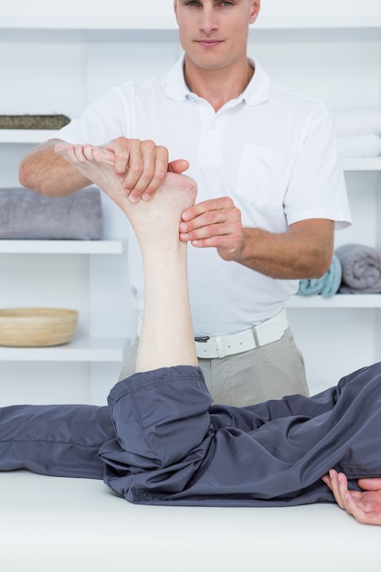 Fisioterapista che fa massaggio alle gambe al suo paziente