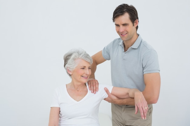 Fisioterapista che massaggia il braccio di una donna senior sorridente