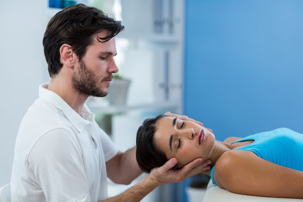 Fisioterapista maschio che dà massaggio capo al paziente femminile