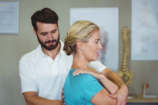 Fisioterapista maschio che dà massaggio del braccio al paziente femminile