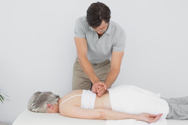 Fisioterapista maschio che massaggia indietro la parte posteriore di una donna senior