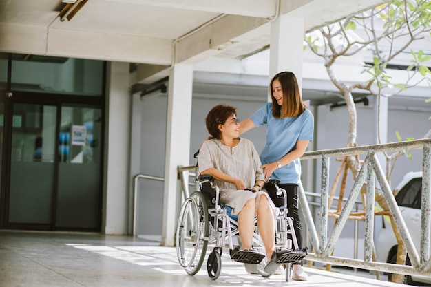 Fisioterapista sorridente che prende cura del paziente senior felice in sedia a rotelle