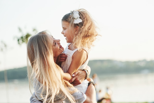 Fissandoci l'un l'altro. Ritratto di mamma e figlia sorridente all'esterno nel parco.