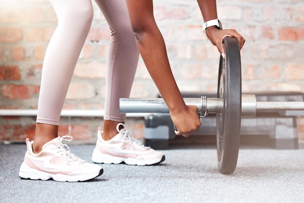 Fissare il peso donna e mani fitness con scarpe da allenamento facendo allenamento bodybuilder Palestra per esercizi di salute e sport di forza muscolare di una persona che tiene pesi per bodybuilding per benessere sportivo