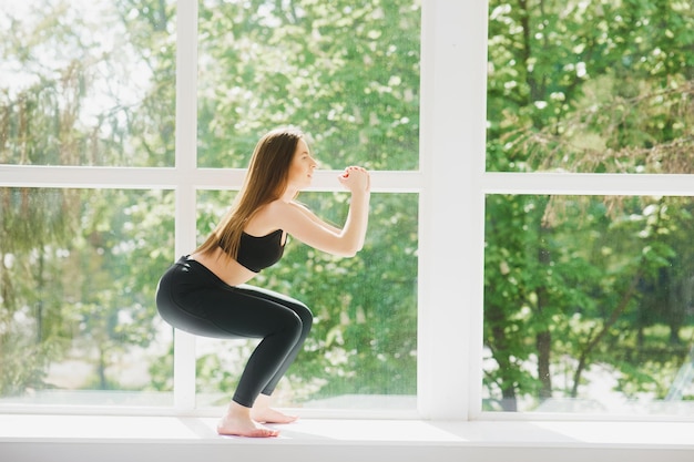 Fit donna posa yoga che si esercita in studio sopra la finestra panoramica