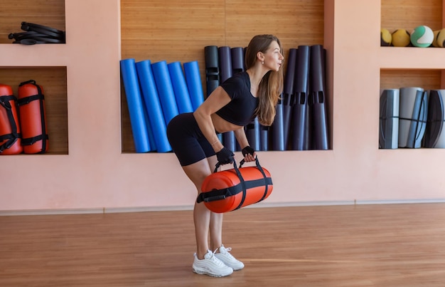 Fit slim giovane donna che si allena con la borsa dei pesi durante la lezione di ginnastica