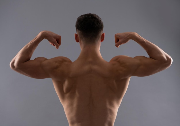 Fit uomo torso posteriore flex braccio muscolo che mostra bicipite tricipite sfondo grigio, flessione.