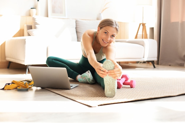Fitness bella donna sottile facendo esercizi di stretching fitness a casa nel soggiorno. Restare a casa attività. Sport, stile di vita sano.