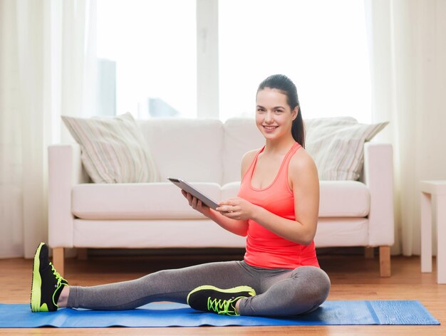 fitness, casa, tecnologia e concetto di dieta - sorridente ragazza adolescente che si allunga sul pavimento con un computer tablet pc a casa